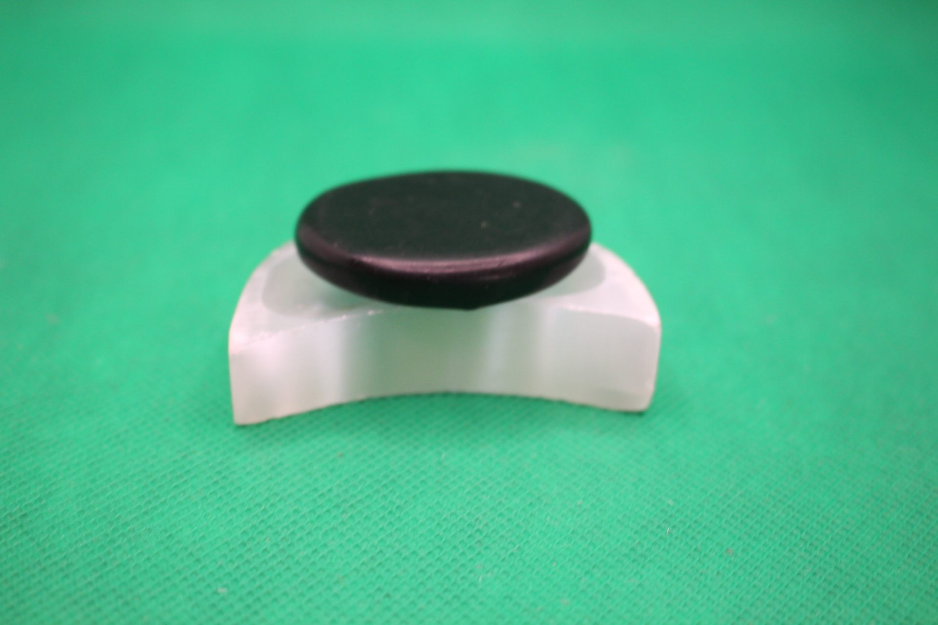 moon-shaped selenite plate with shungite palm stone on it