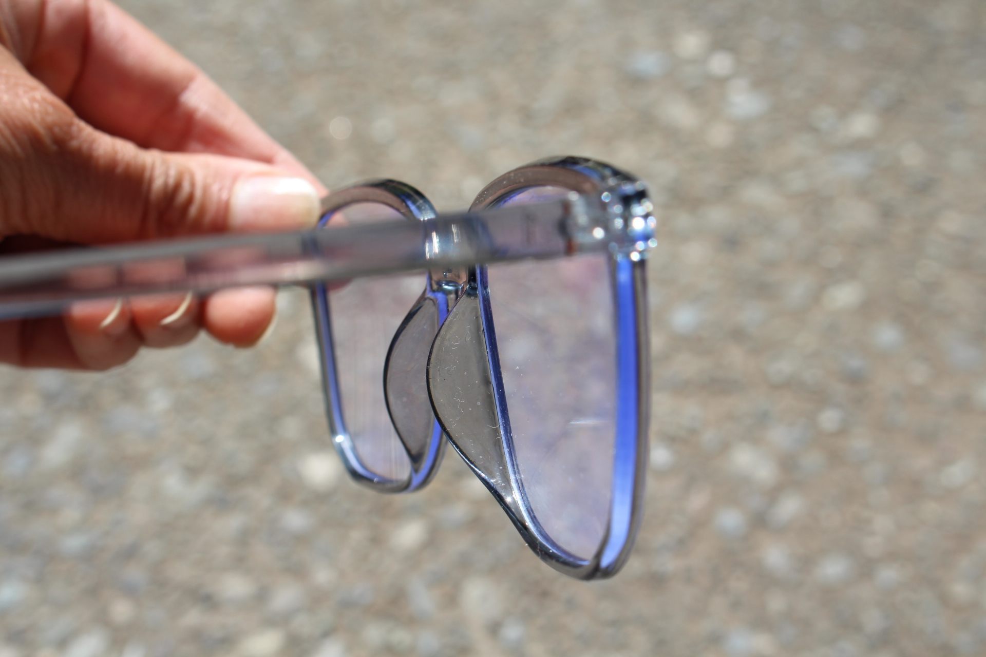 side view of blue-light-filtering glasses reflecting a blue glow under the sun