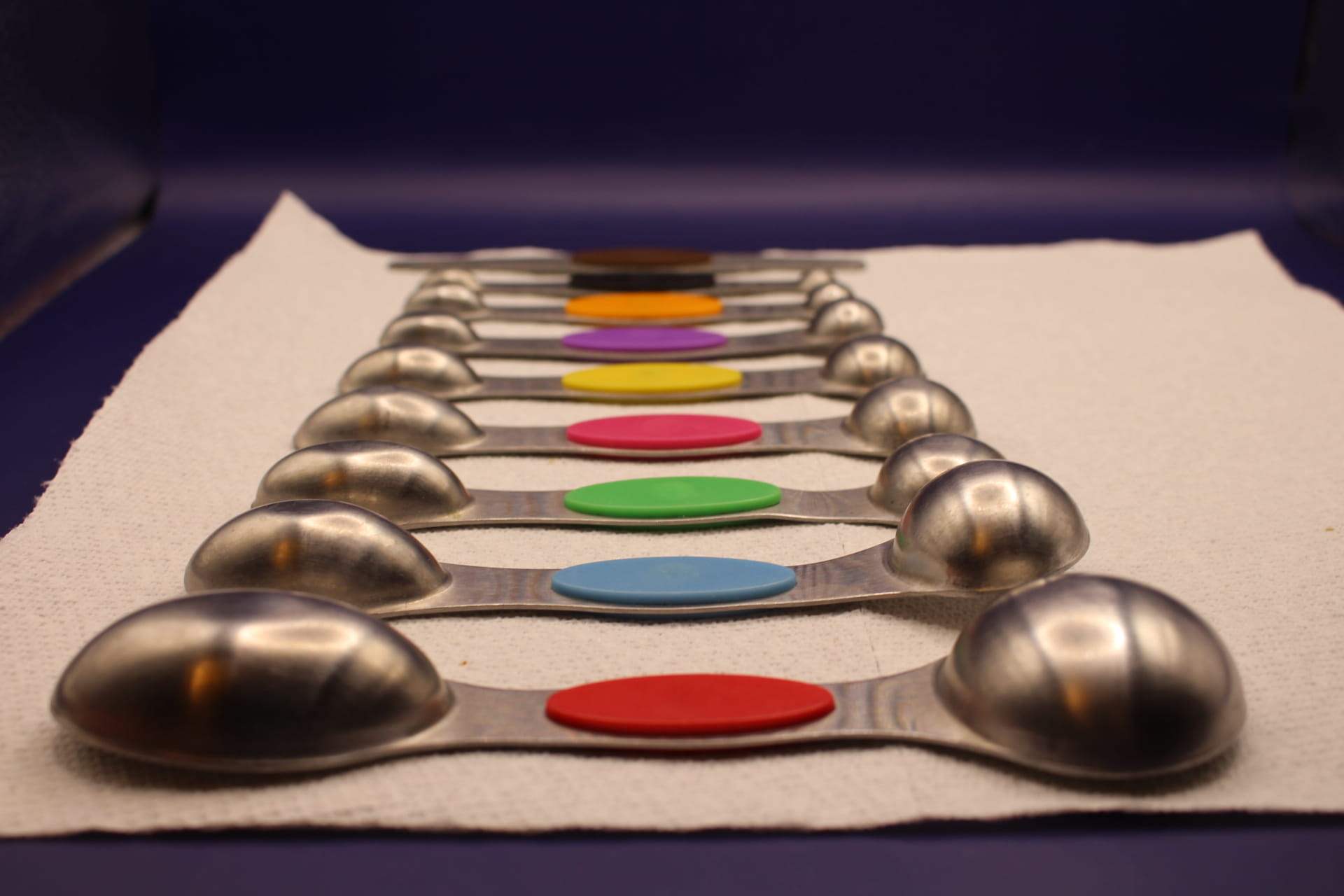 two-sided magnetic measuring spoon set with leveler tool, showing the bottoms of the spoons, with the largest spoon at the front