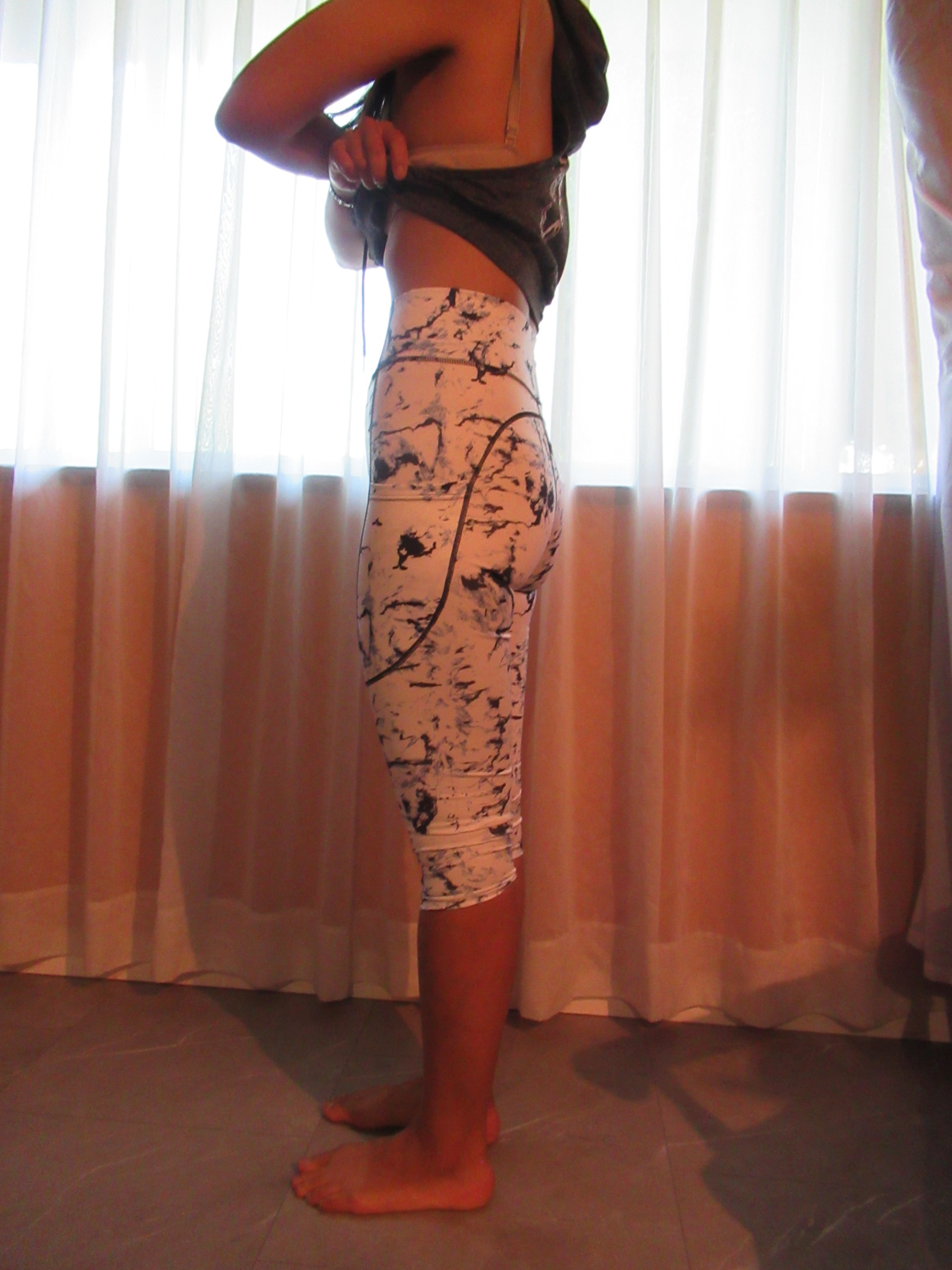 butt-lifting capri pants with big pockets set of three -- white with black splash design, left side view; trying on, modelling butt-lifter capris on person