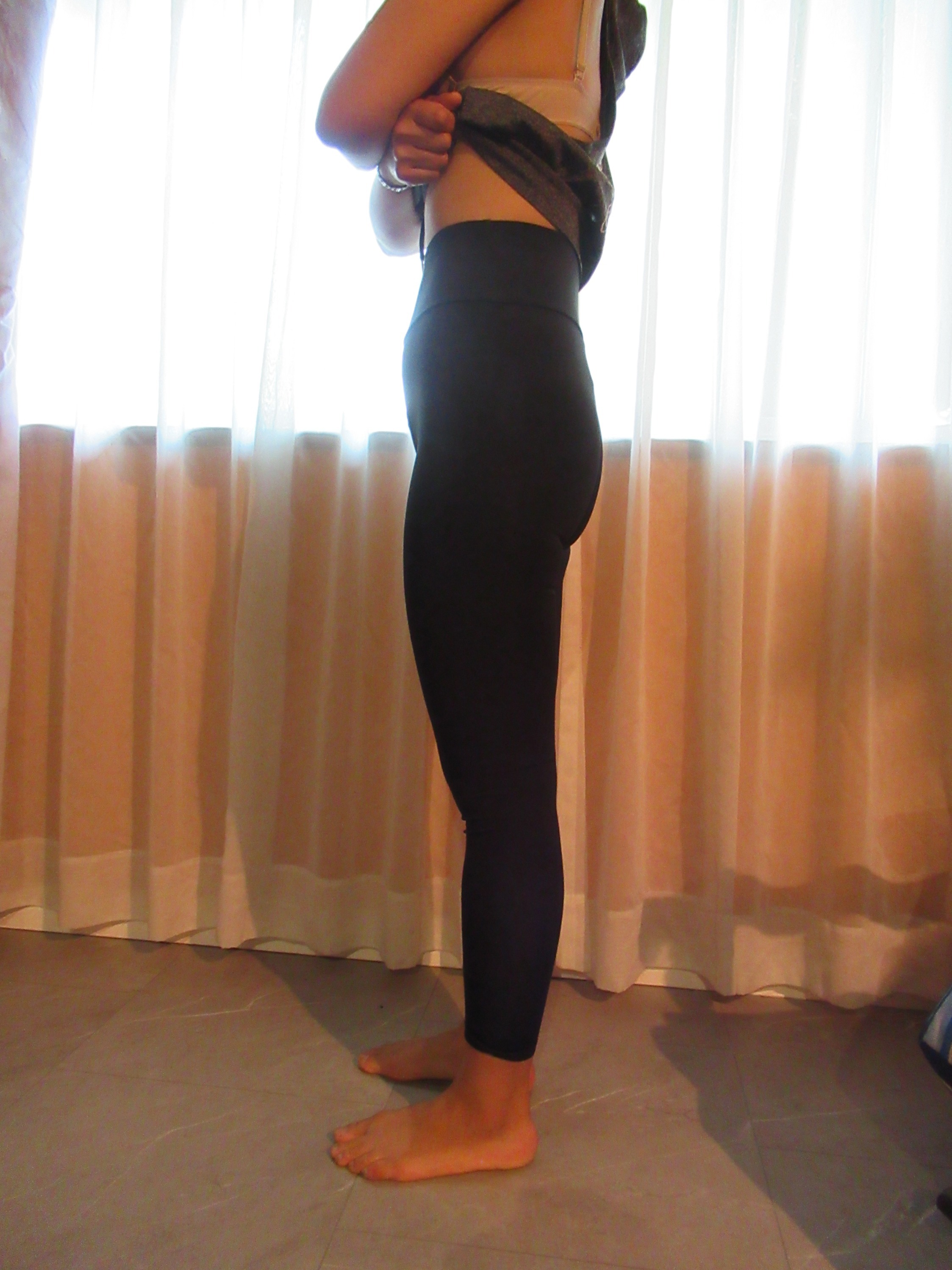 butt-lifting bike pants / yoga leggings -- black, left side view; trying on, modelling biking butt-lifter on person