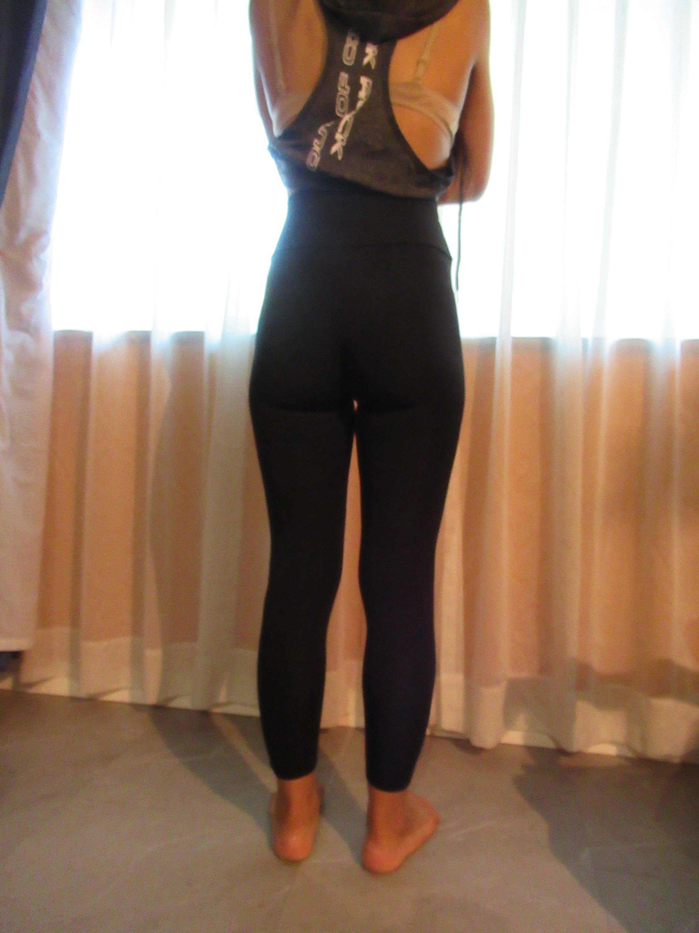 butt-lifting bike pants / yoga leggings -- black, back view; trying on, modelling biking butt-lifter on person