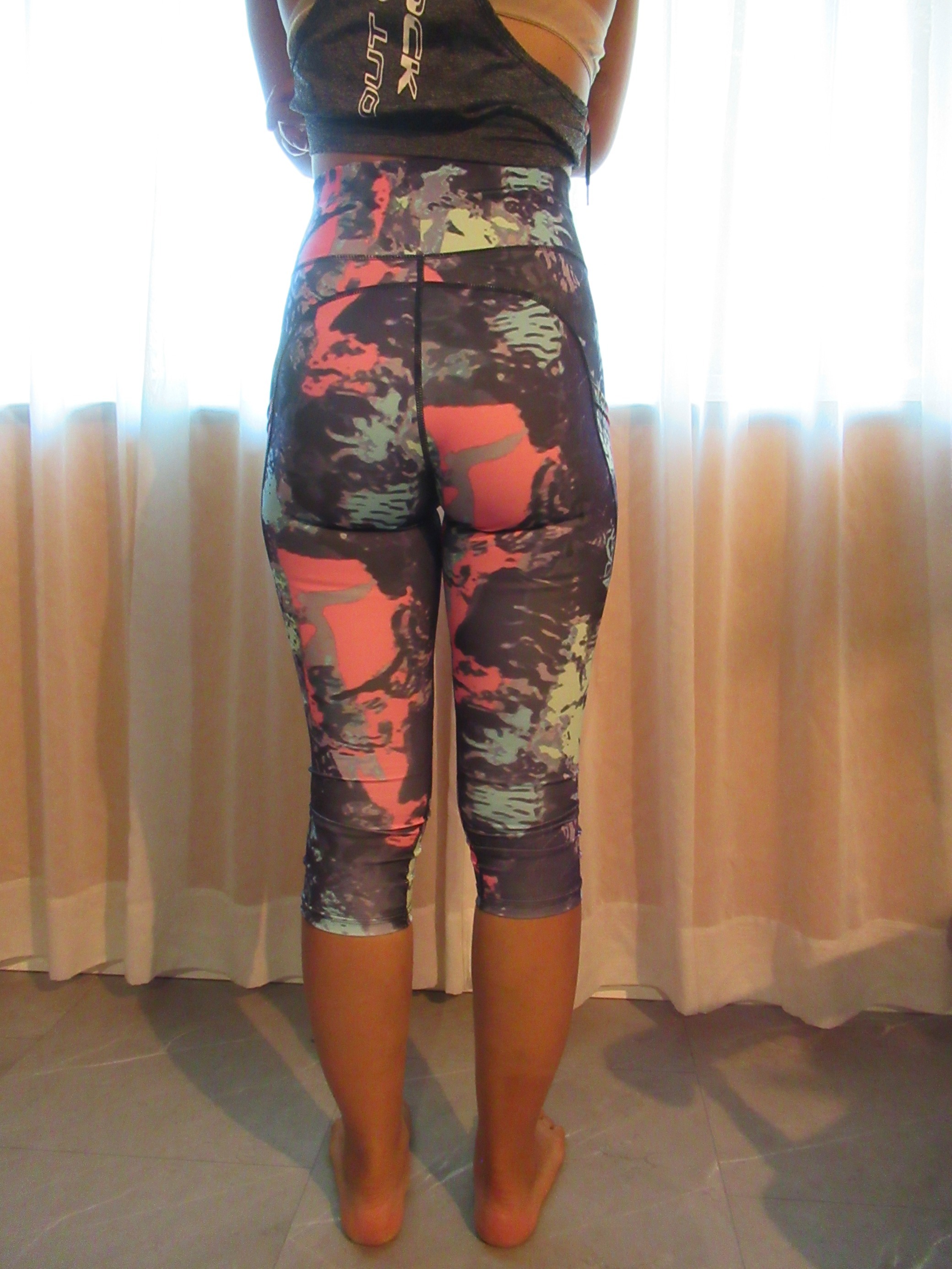 butt-lifting capri pants with big pockets set of three -- purple with pink/green/blue splash design, back view; trying on, modelling butt-lifter capris on person