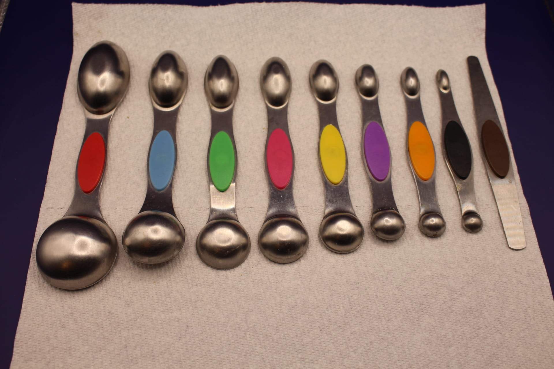 magnetic measuring spoons set stainless steel with leveler, showing bottoms of spoons, from biggest to smallest sizes