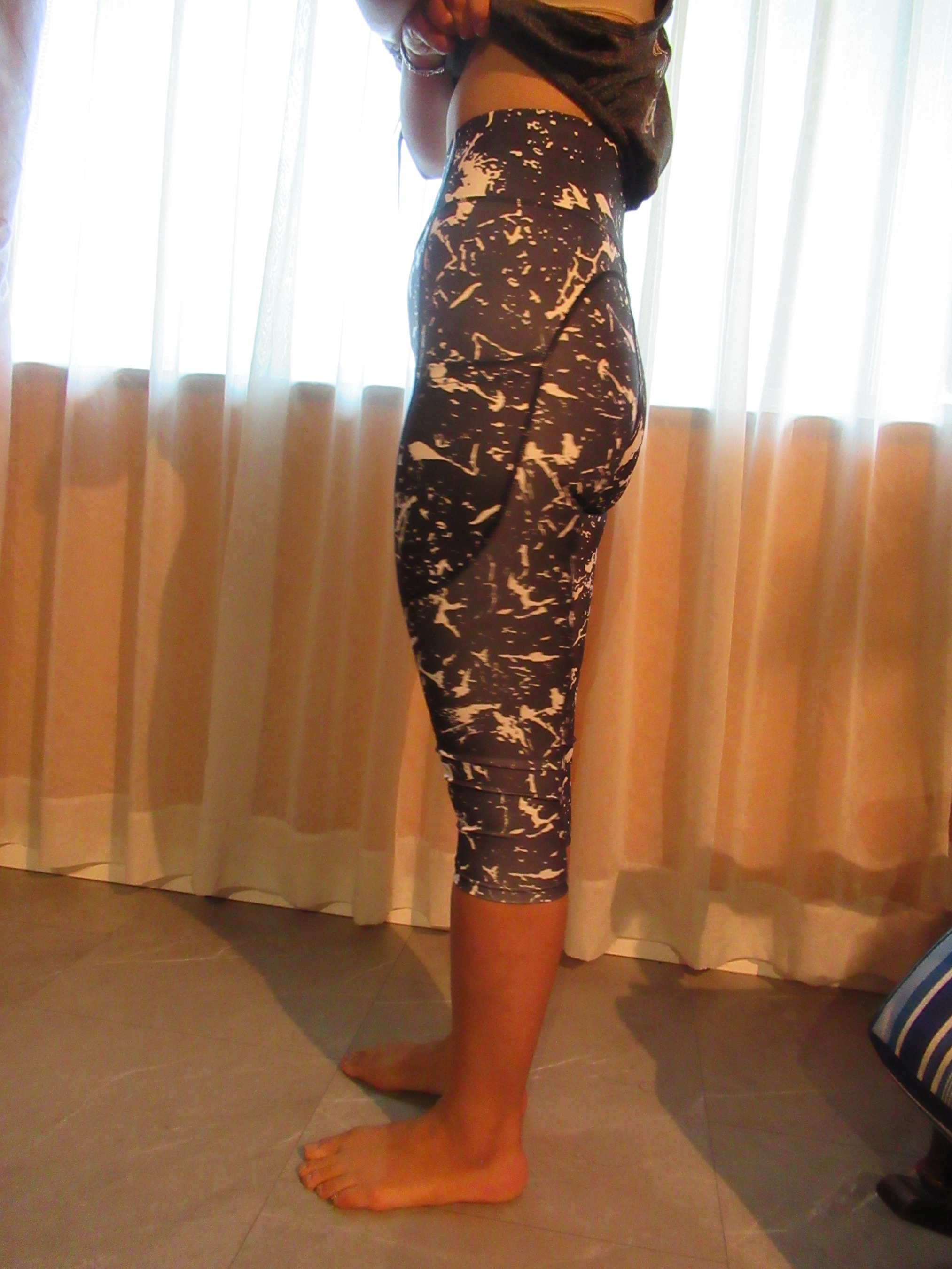 butt-lifting capri pants with big pockets set of three -- black with white splash design, left side view; trying on, modelling butt-lifter capris on person