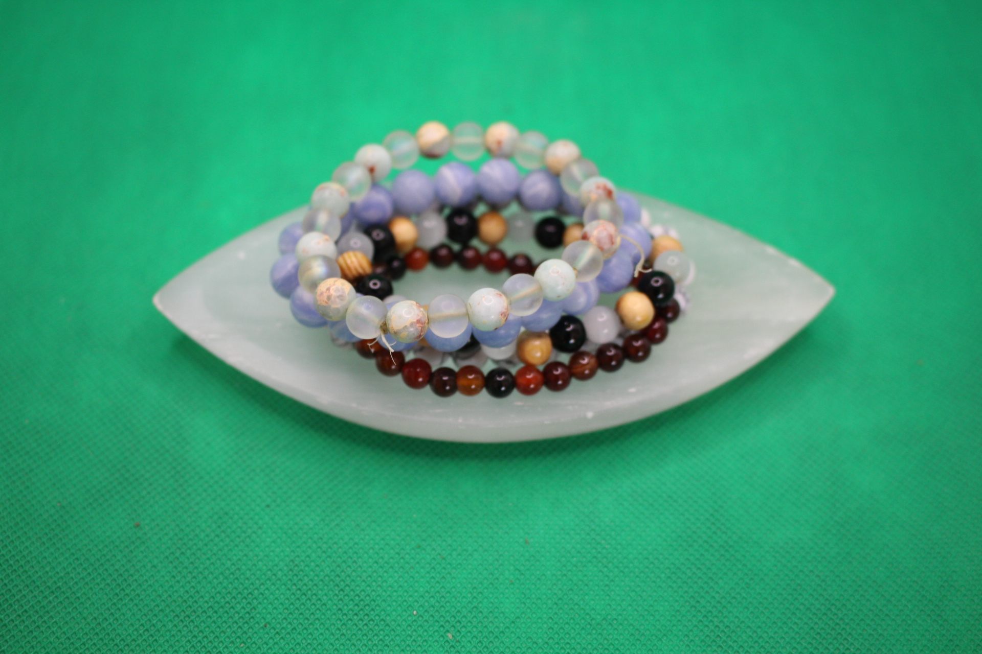 leaf-shaped selenite plate with bracelets piled on it